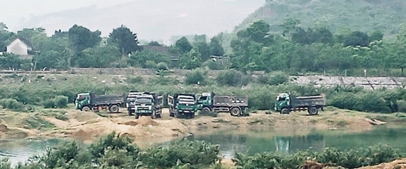 Hàng chục chiếc xe tải chờ trên bờ sông để chở cát.