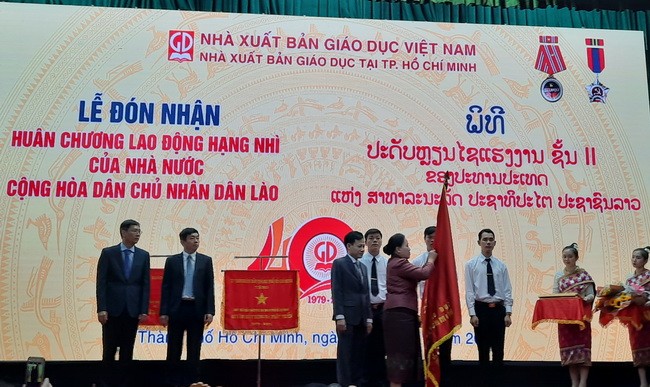 Bà Khathaly Siliphongphan, Thứ trưởng Bộ Giáo dục và Thể thao nước CHDCND Lào gắn Huân chương Lao động hạng II trên cờ truyền thống của NXBGD tại TPHCM