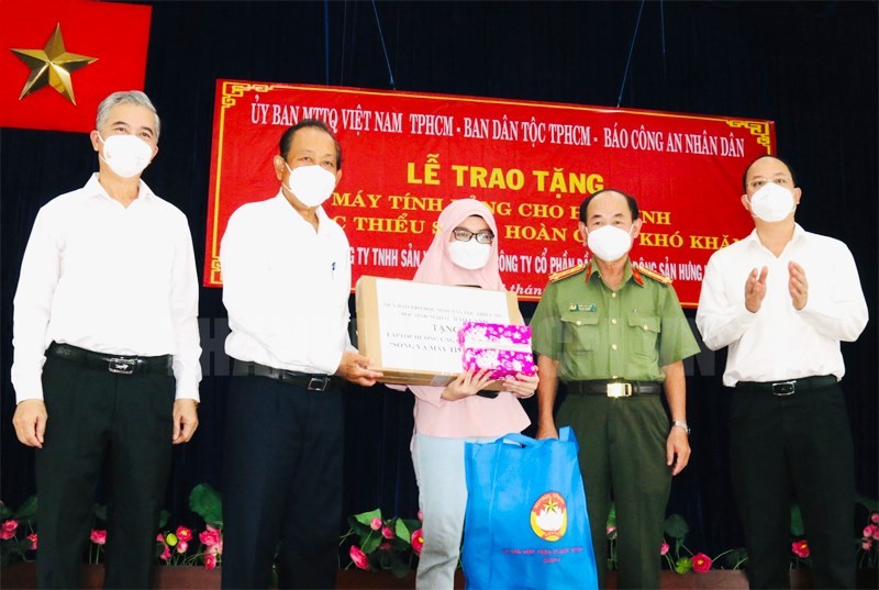 Nguyên Phó Thủ tướng thường trực Chính phủ Trương Hòa Bình cùng đại diện lãnh đạo TP Hồ Chí Minh trao tặng máy tính xách tay cho em Asikine Hồng, học sinh lớp 12 Trường THPT Tạ Quang Bửu (Ảnh: Thành ủy TP).