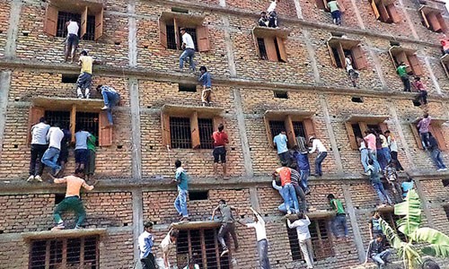 Phụ huynh và người thân thí sinh bất chấp nguy hiểm để leo lên tầng cao ném tài liệu cho con em tại một điểm thi ở quận Vaishali, bang Bihar. Ảnh: Hindustan Times.