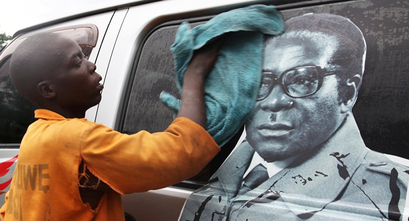 Một cậu bé đang lau bức ảnh Tổng thống Zimbabwe Robert Mugabe 