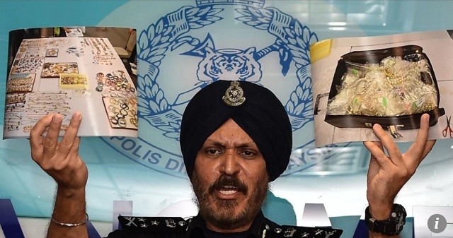 Giám đốc Phòng điều tra tội phạm thương mại cầm những ảnh chụp đồ thu giữ được từ nơi ở của cựu lãnh đạo Malaysia Najib Razak