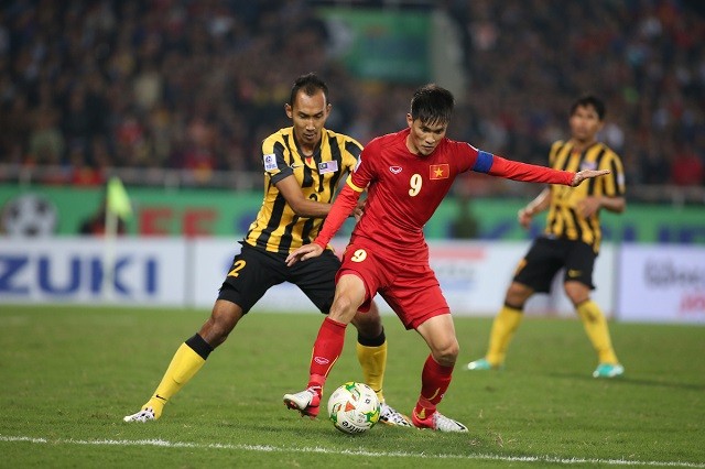 Cầu thủ Việt Nam và Malaysia tranh bóng trên sân