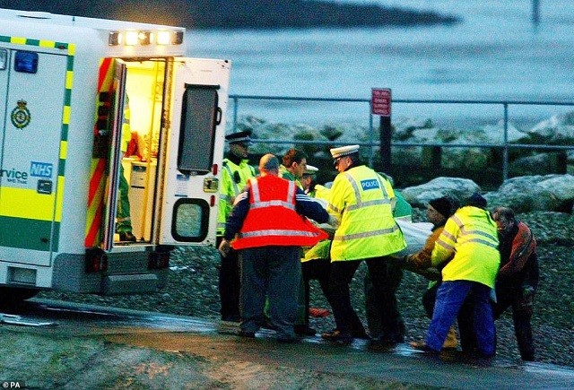 Cảnh sát và nhân viên cứu hộ mang xác các nạn nhân Trung Quốc nhặt sò bị mắc kẹt do thủy triều dâng cao vào xe cứu thương tại Morecambe vào tháng 2/2004.