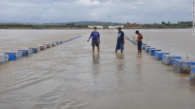 Người dân Philippines trên một cây cầu ngập nước do mưa bão.