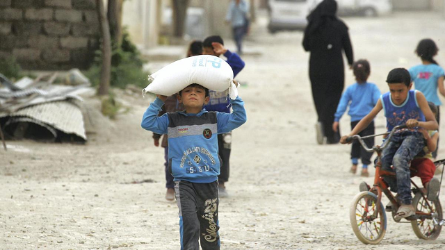 Một cậu bé mang thực phẩm do Chương trình Lương thực Thế giới của LHQ cung cấp ở Raqqa, Syria  - về nhà.