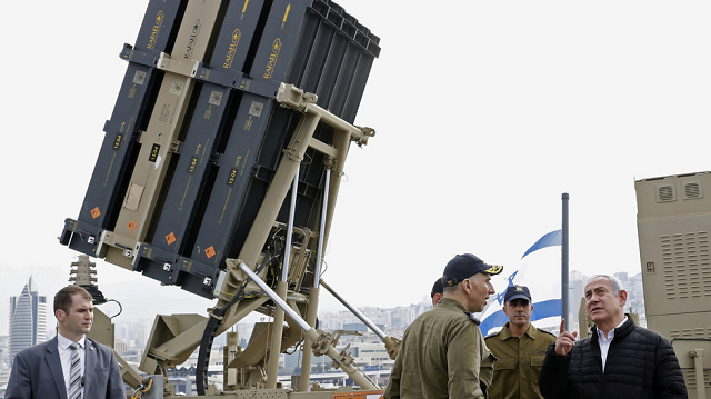 Thủ tướng Israel Benjamin Netanyahu (áo đen) đứng gần hệ thống đánh chặn Vòm sắt.
