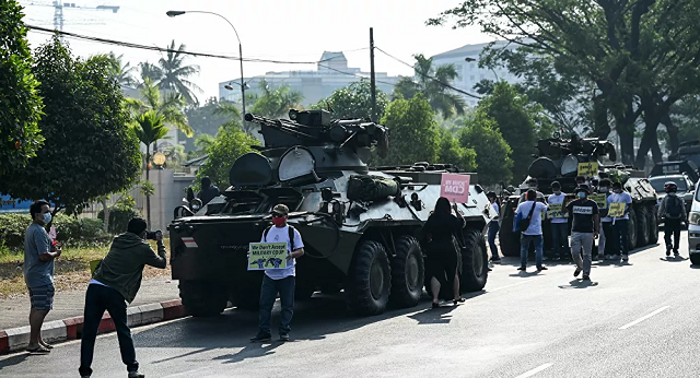 Người biểu tình có mặt bên cạnh các phương tiện của quân đội Myanmar.