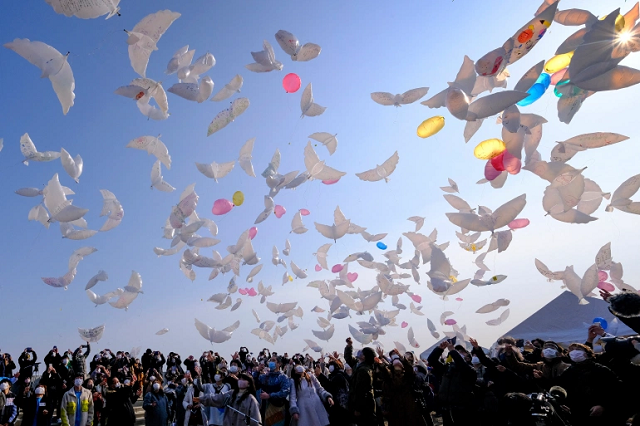 Mọi người thả bóng bay hình chim bồ câu lên trời để tưởng nhớ các nạn nhân động đất và sóng thần ở Natori, tỉnh Miyagi ngày 11/3/2021 