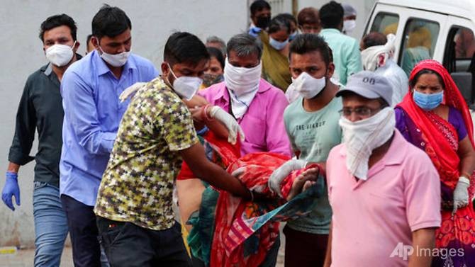 Người thân khiêng một phụ nữ ngất xỉu sau khi nhìn thấy thi thể của chồng tại bệnh viện COVID-19 của chính phủ ở Ahmedabad, Ấn Độ, vào ngày 27/4