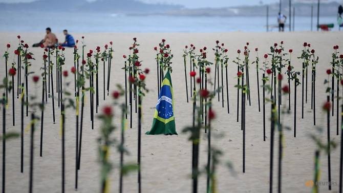Cờ Brazil giữa những bông hoa đỏ do tổ chức phi chính phủ Rio de Paz đặt trên bãi biển Copacabana để tưởng nhớ đối với nửa triệu người Brazil thiệt mạng vì COVID-19 