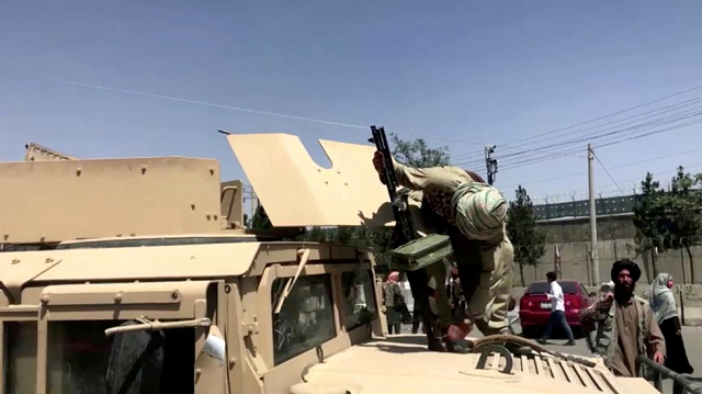Một chiến binh Taliban nạp lại súng máy của mình trên chiếc xe bọc thép Humvee do Mỹ sản xuất mà họ giành được ở Kabul, Afghanistan. 