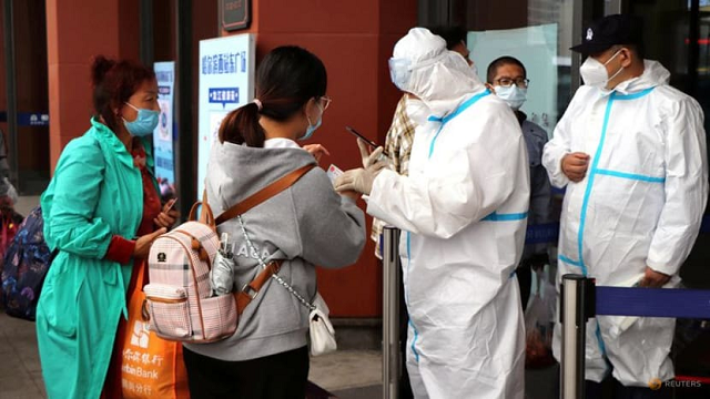 Nhân viên mặc đồ bảo hộ kiểm tra bằng chứng về kết quả xét nghiệm Covid-19 âm tính đối với du khách tại lối vào Ga xe lửa Tây Cáp Nhĩ Tân, Trung Quốc.