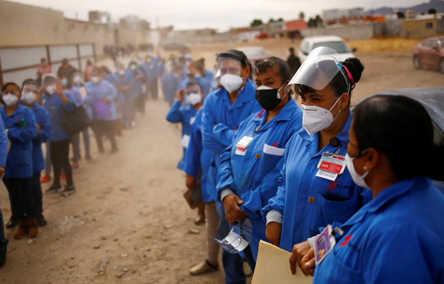 Nhân viên của một nhà máy lắp ráp chờ xe buýt sau khi tiêm nhắc lại vắc xin AstraZeneca COVID-19 trong một chương trình tiêm chủng hàng loạt cho những người trên 50 tuổi, ở Ciudad Juarez, Mexico.