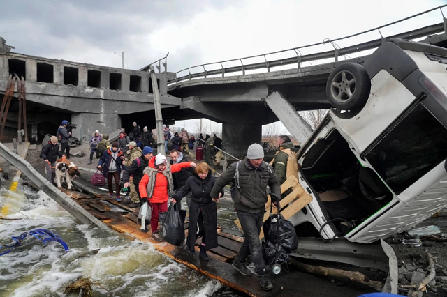 Mọi người băng qua một lối đi dưới một cây cầu bị phá hủy trong khi chạy trốn khỏi thị trấn Irpin gần Kiev vào thứ Hai 