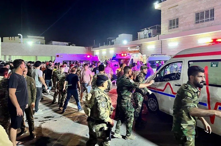 Binh sĩ và nhân viên cứu hộ tập trung xung quanh xe cứu thương chở nạn nhân vụ cháy ở bên ngoài Bệnh viện Đa khoa Hamdaniyah ở Al-Hamdaniyah, Iraq.