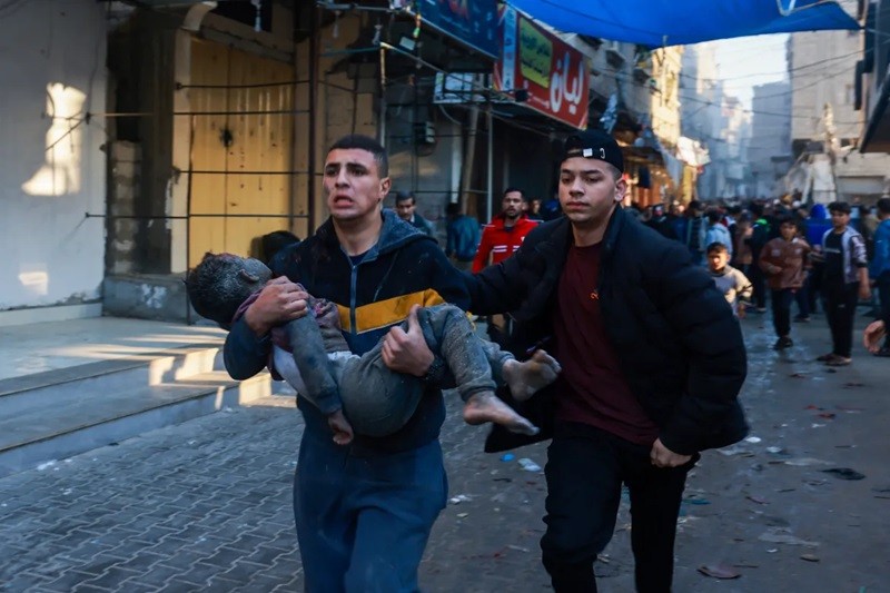 Một người Palestine bế cậu bé bị thương trong vụ ném bom của Israel sau khi lệnh ngừng bắn tạm thời hết hạn. (Ảnh: Mohammed Abed/AFP).