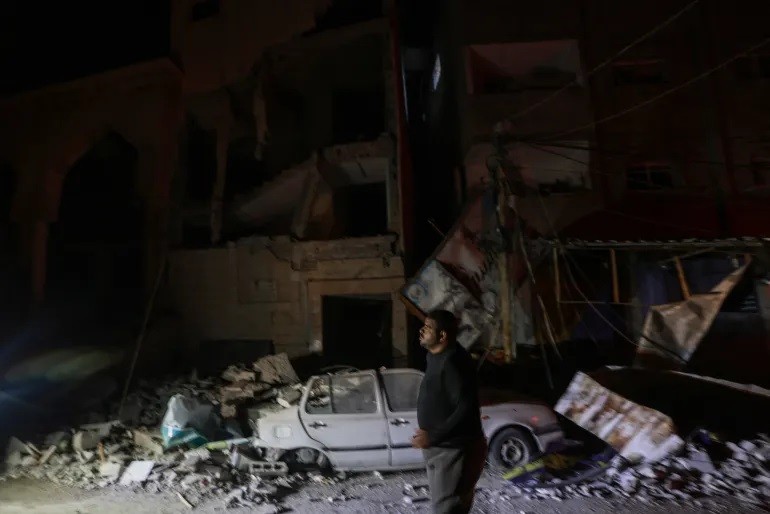 Một người đi ngang qua tòa nhà bị phá hủy sau vụ ném bom của Israel vào Rafah vào sáng 12/2 (Ảnh: Mohammed Abed/AFP)