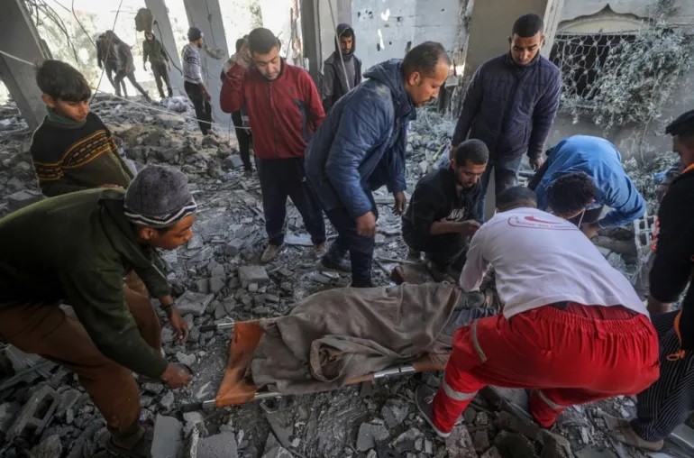 Người Palestine bê một thi thể từ đống đổ nát của một ngôi nhà bị phá hủy sau cuộc không kích của Israel ở Deir el-Balah, trung tâm Dải Gaza, ngày 22 tháng 2 năm 2024 (Ảnh: Mohammed Sabre/EPA]