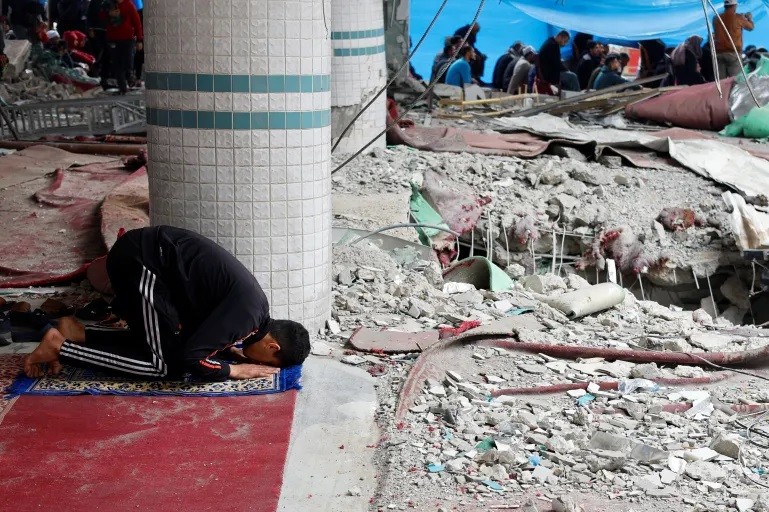 Một người Palestine cầu nguyện ngày thứ Sáu tại đống đổ nát của một nhà thờ. (Ảnh: Reuters).
