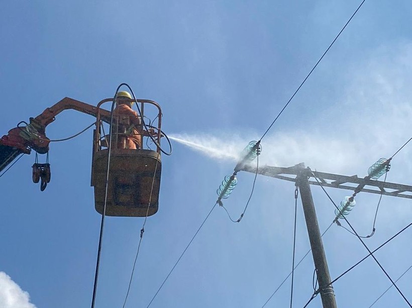 Công nhân Công ty Điện lực Điện Biên thực hiện rửa sứ hotline trên lưới điện.