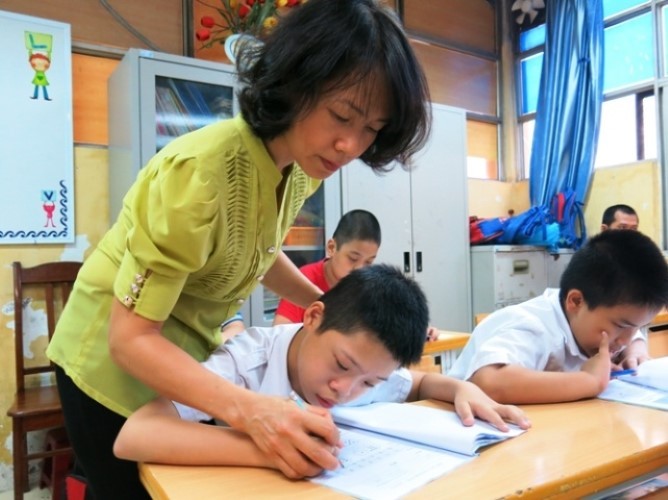 Giáo viên Trường TH Bình Minh luyện chữ cho học sinh khuyết tật. 