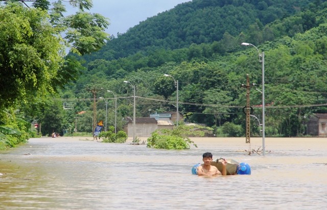 Người dân thôn Đa Đụn, xã Thành Trực, huyện Thạch Thành (Thanh Hóa) bơi giữa dòng nước lũ.