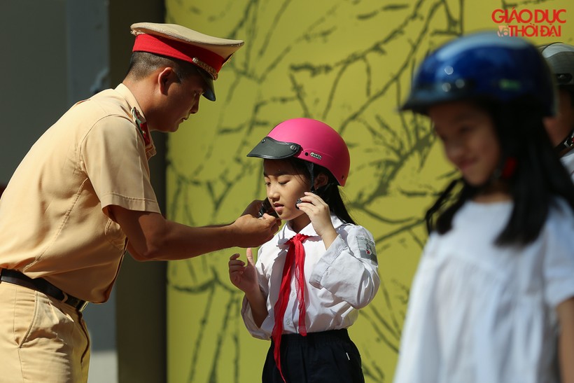 Học sinh tiểu học được hướng dẫn đội mũ bảo hiểm đúng cách để an toàn khi tham gia giao thông.