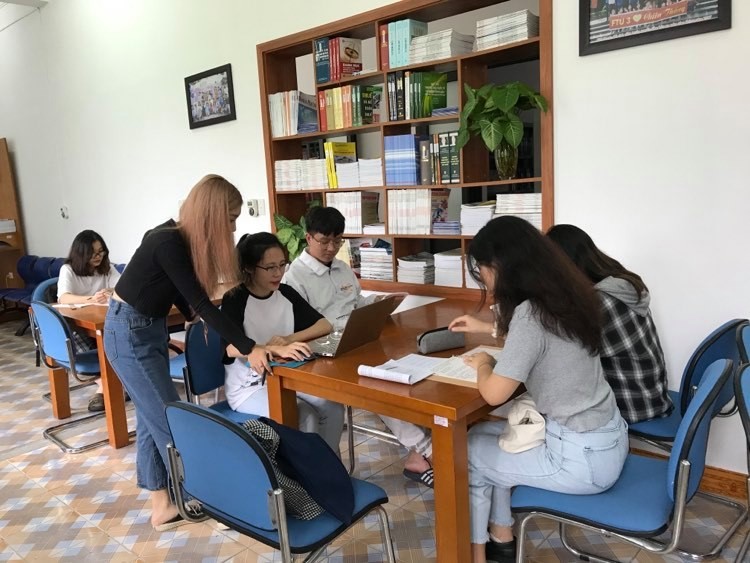 Nhóm 5 bạn sinh viên đang thảo luận một mô hình kinh doanh ảo tại thư viện trường.
