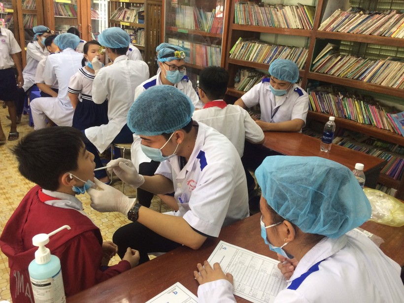 Các bác sĩ thực hiện khám chữa răng cho học sinh