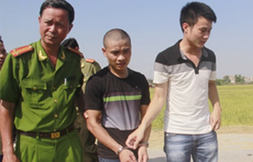 Hung thủ Nguyễn Văn Hải (áo đen) bị cảnh sát áp giải về nơi gây án tìm hung khí 