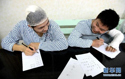 Liu Yanbing (trái) và Yi Zhengyong hôm 17/6 cầm bút viết tại Bệnh viện Nhân dân Yichun, tỉnh Giang Tây, đông nam Trung Quốc