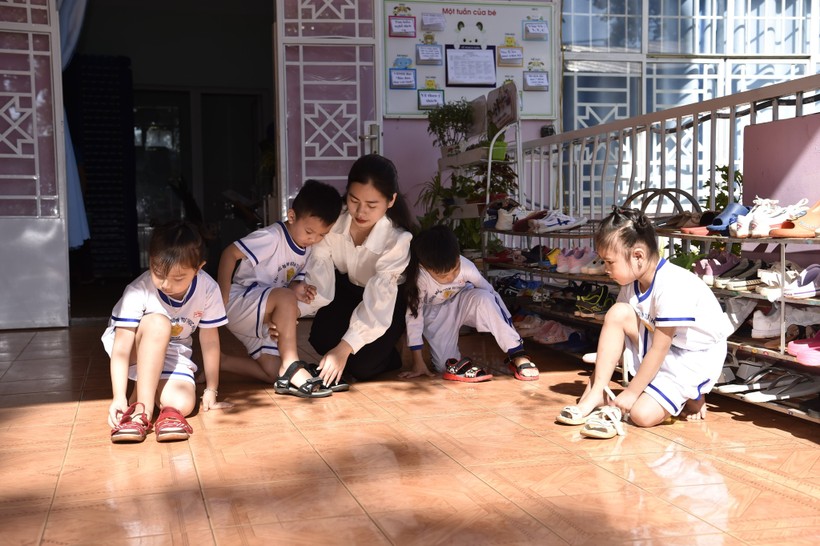 Cô giáo trường MN Họa Mi - TP Buôn Ma Thuột hướng dẫn trẻ đi dép đúng cách (ảnh: TT).
