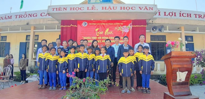 Thầy giáo Nguyễn Văn Tý trao quà cho học sinh khó khăn.