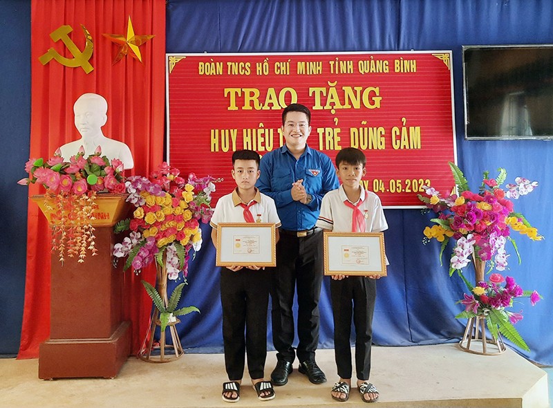Đại diện Tỉnh Đoàn Quảng Bình trao Huy hiệu "Tuổi trẻ dũng cảm" của Trung ương Đoàn cho hai học sinh. 
