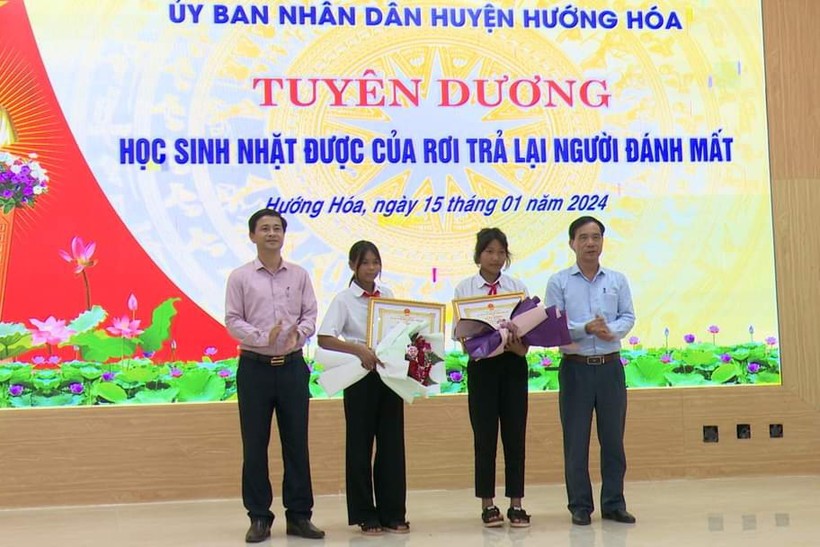 Ông Trần Bình Thuận, Chủ tịch UBND huyện (bên trái) và ông Phạm Trọng Hổ, Phó Chủ tịch UBND huyện đã biểu dương và tặng giấy khen cho hai học sinh Hồ Thị Hinh và Hồ Thị Nhỉ.