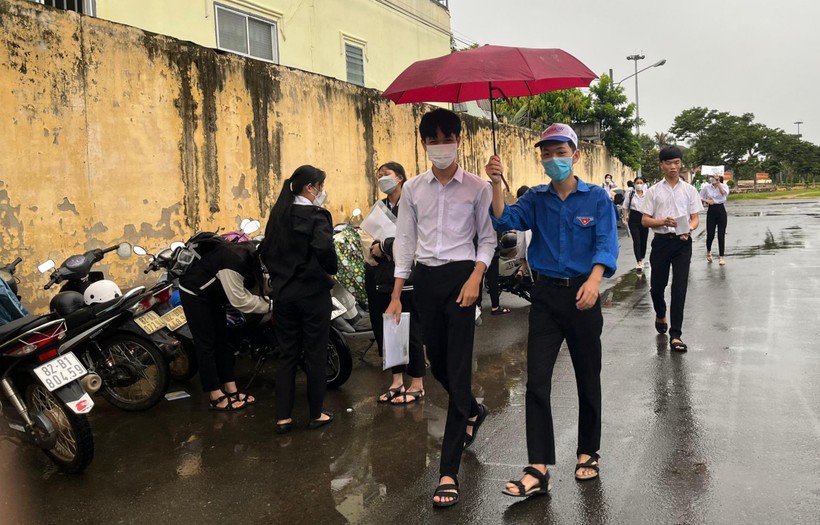 Tình nguyện viên tại Kon Tum hỗ trợ che mưa cho thí sinh vào điểm thi.