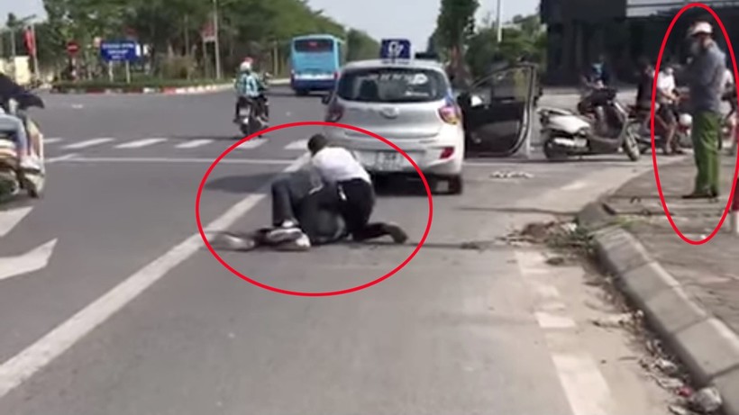 Anh Nguyễn Trần Minh vật lộn với tên cướp, trong khi người mặc quần xanh đứng bấm điện thoại. Ảnh cắt từ Clip