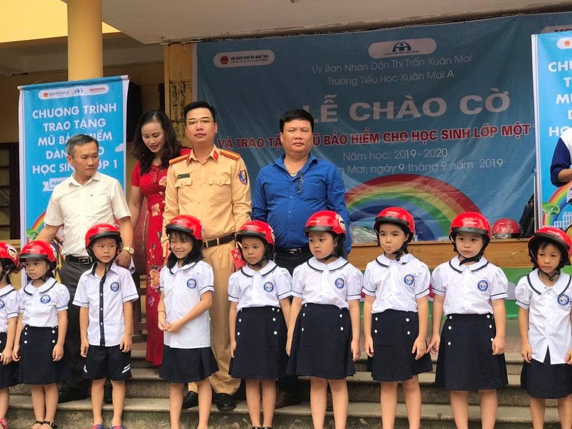 Thiếu tá Trương Việt Sơn và đại diện Công ty ôtô xe máy Khai Phát trao tặng mũ bảo hiểm cho các em học sinh.