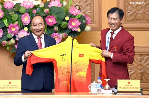 Thủ tướng nhận qùa là đồng phục của đội tuyển Việt Nam có các chữ ký của các vận động viên đạt huy chương tại giải thể thao Asiad 