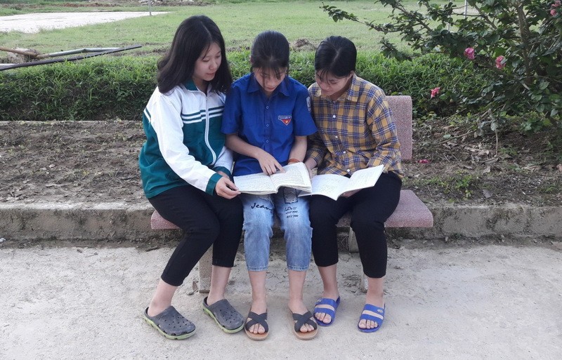 Em Lý Thị Minh mặc áo xanh (giữa), đang cùng các bạn trong lớp thảo luận nhóm.
