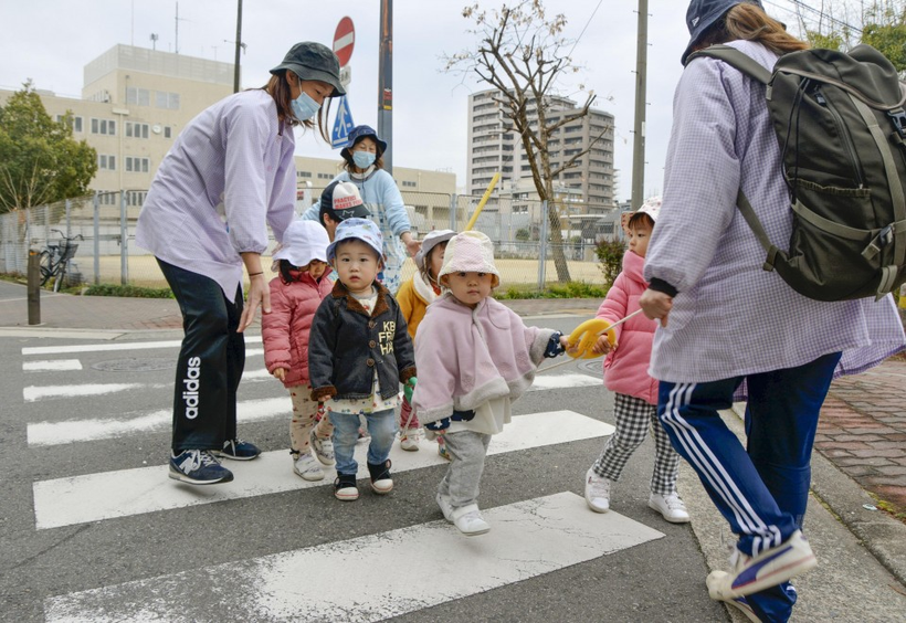 Giáo viên mầm non đi dạo với trẻ em ở thành phố Osaka.