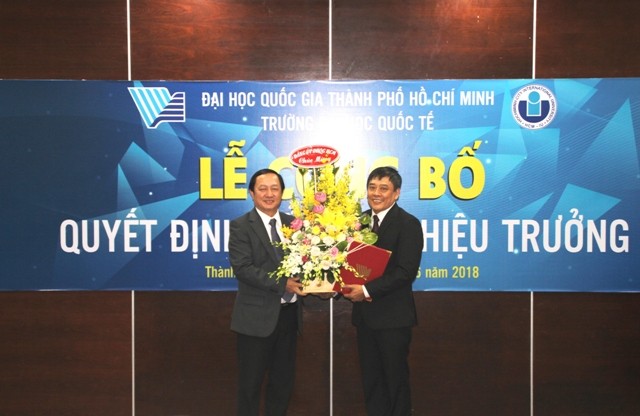  PGS.TS Huỳnh Thành Đạt - Giám đốc ĐHQG TPHCM trao quyết định và tặng hoa chúc mừng TS. Trần Tiến Khoa (phải)