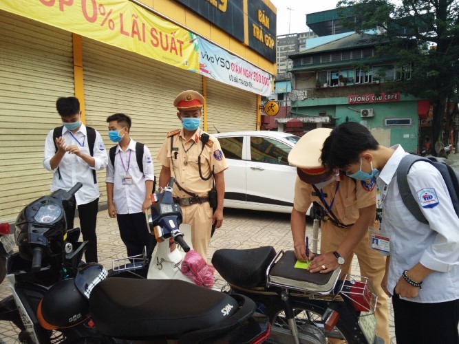Lực lượng chức năng kiểm tra, nhắc nhở học sinh đi xe máy tới trường.