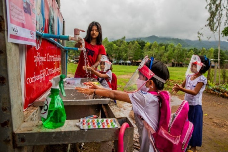 Học sinh tại bang Mon (Myanmar) rửa tay khi tới lớp.