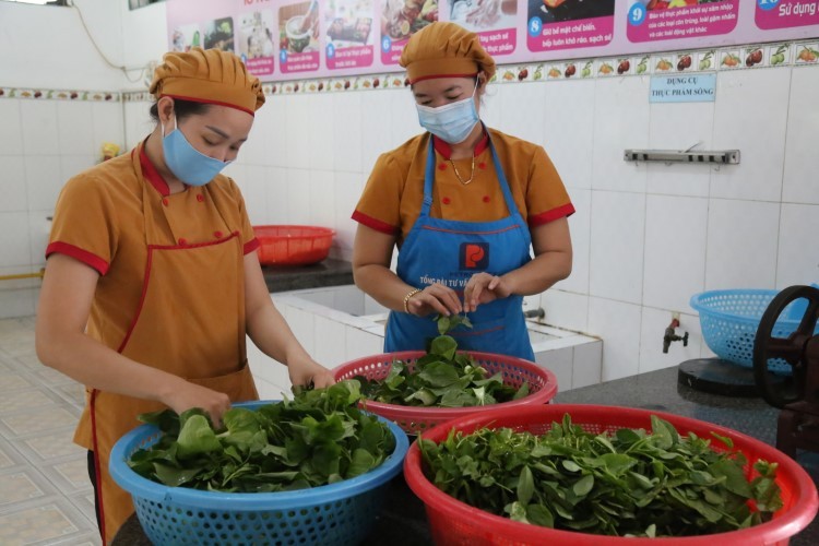 Nhân viên dinh dưỡng Trường Mầm non Hoa Hồng (TP Đồng Hới) chọn lọc và làm sạch rau xanh để nấu cho trẻ.