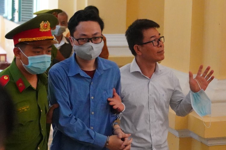 Bị cáo Nguyễn Hải Nam và Lâm Hoàng Tùng được hộ tống ra xe, sau khi phiên tòa bị hoãn. Ảnh: CTV