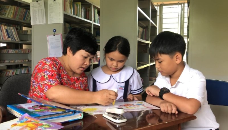 Cô Lê Thị Quỳnh Ly hướng dẫn các em học sinh “vá” từng cuốn sách bị rách.