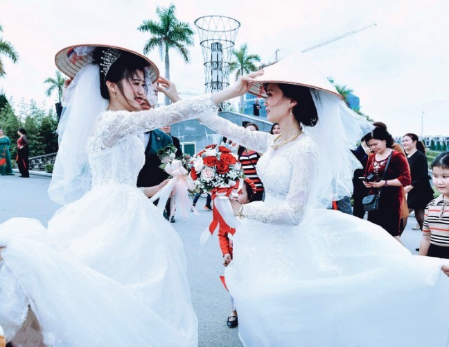 Hai cô dâu trao nón cho nhau để cầu chúc may mắn.