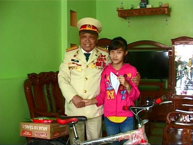 Một em nhỏ được ông Tự trao xe đạp và quà trong chương trình khuyến học.
